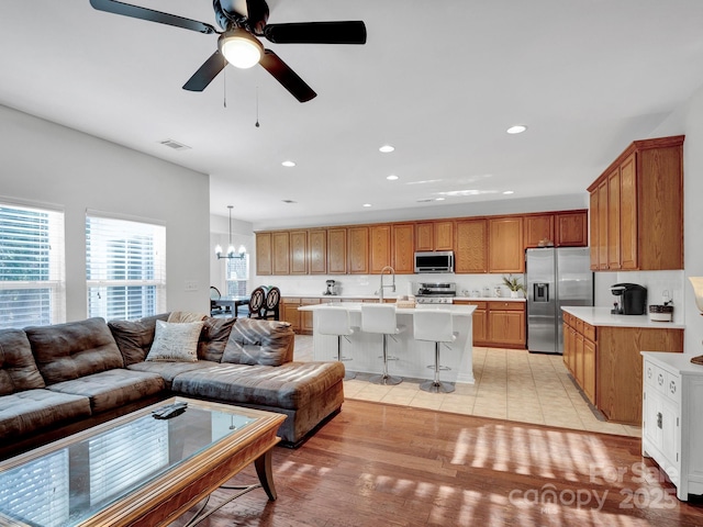 living room with light wood-type flooring and ceiling fan with notable chandelier