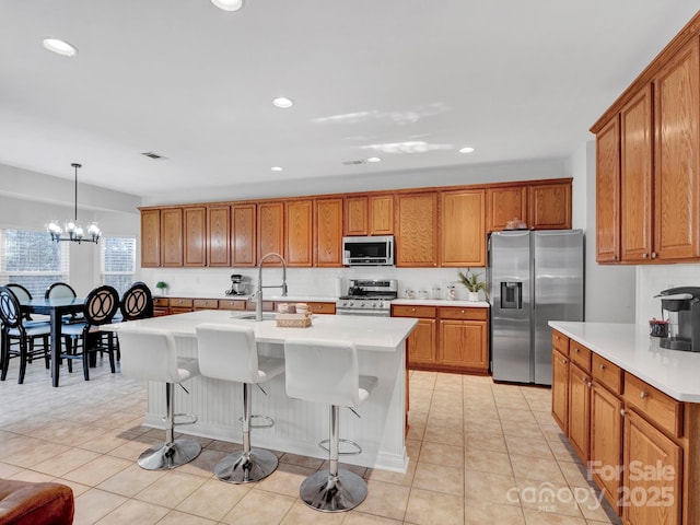 kitchen featuring a notable chandelier, sink, hanging light fixtures, a kitchen island with sink, and appliances with stainless steel finishes