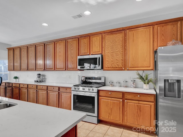 kitchen with light tile patterned flooring, stainless steel appliances, and backsplash