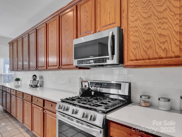 kitchen with light tile patterned floors, backsplash, and stainless steel appliances