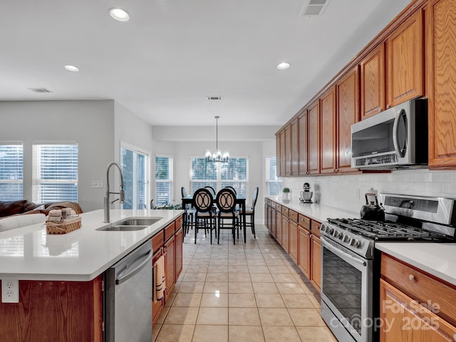 kitchen featuring decorative light fixtures, a center island with sink, sink, appliances with stainless steel finishes, and a chandelier