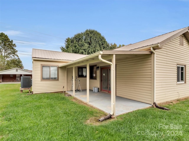 rear view of property with a lawn, a patio, and cooling unit