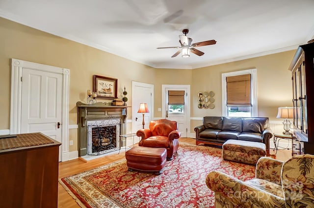 living room featuring crown molding, light wood-type flooring, and ceiling fan