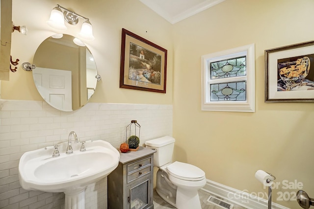 bathroom featuring toilet, crown molding, tile walls, and sink