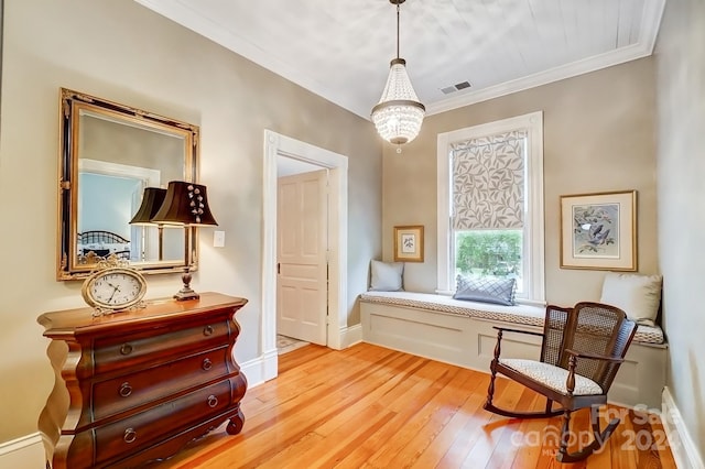 living area featuring hardwood / wood-style flooring, ornamental molding, and an inviting chandelier