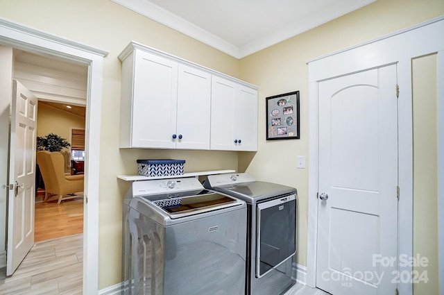 laundry area with light hardwood / wood-style floors, ornamental molding, cabinets, and separate washer and dryer