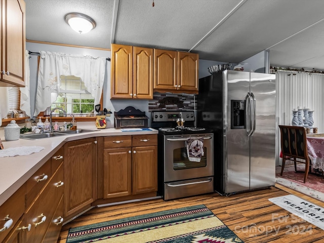 kitchen featuring light hardwood / wood-style floors, tasteful backsplash, stainless steel appliances, a textured ceiling, and sink