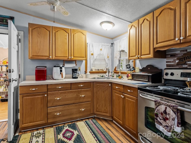 kitchen featuring light wood-type flooring, crown molding, sink, and stainless steel range