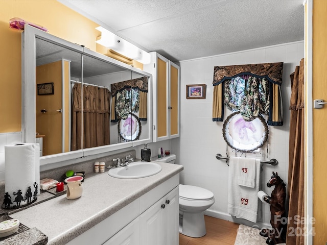 bathroom featuring wood-type flooring, a textured ceiling, a shower with shower curtain, vanity, and toilet