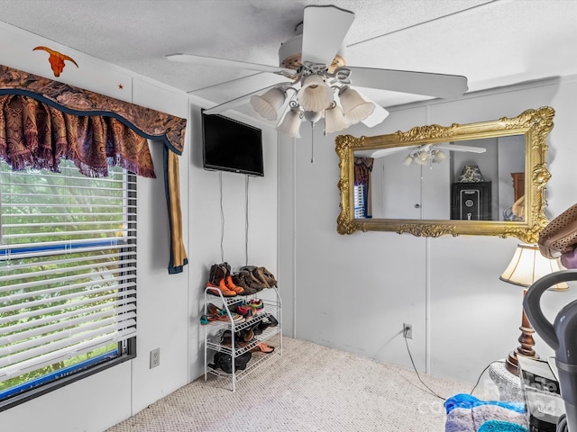 carpeted bedroom featuring ceiling fan and a textured ceiling