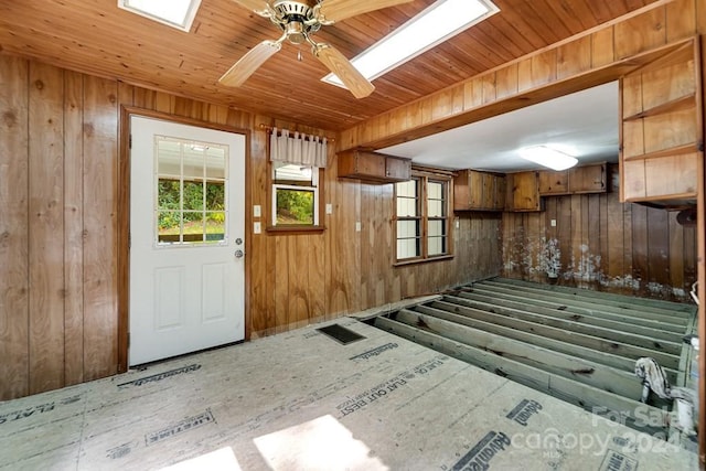 interior space featuring ceiling fan, wood ceiling, and wooden walls