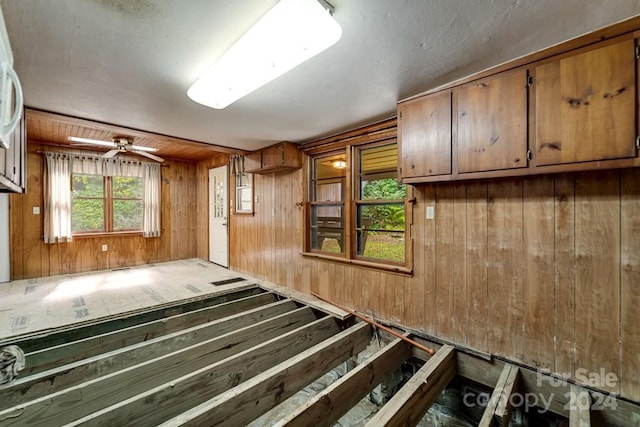 miscellaneous room with ceiling fan and wooden walls