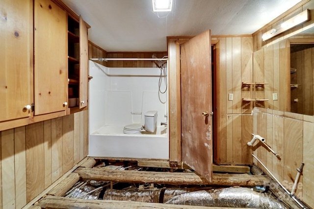 bathroom featuring toilet, a shower, and wooden walls