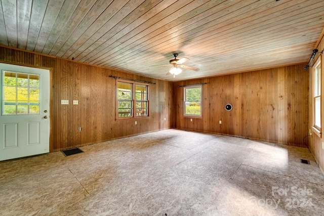 spare room featuring wood walls, wooden ceiling, and ceiling fan