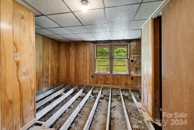 misc room featuring wood walls and a drop ceiling