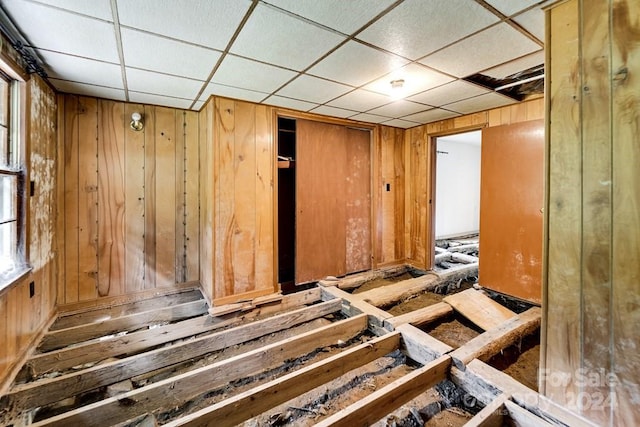 miscellaneous room featuring a paneled ceiling and wooden walls