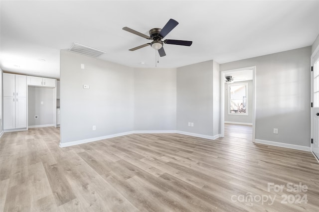 empty room with light wood-type flooring, ceiling fan, and a wealth of natural light