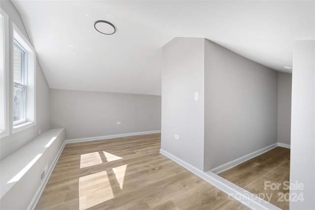 additional living space with light hardwood / wood-style flooring and lofted ceiling