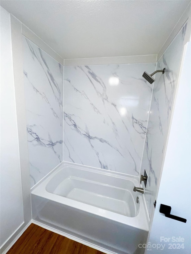 bathroom featuring wood-type flooring and tiled shower / bath