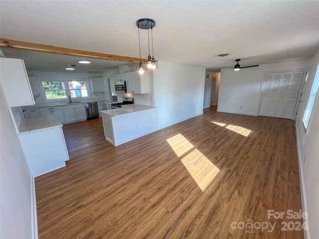 kitchen featuring dark hardwood / wood-style floors, kitchen peninsula, decorative light fixtures, white cabinets, and appliances with stainless steel finishes