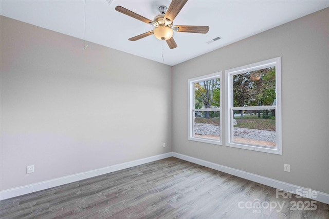 spare room featuring visible vents, ceiling fan, baseboards, and wood finished floors