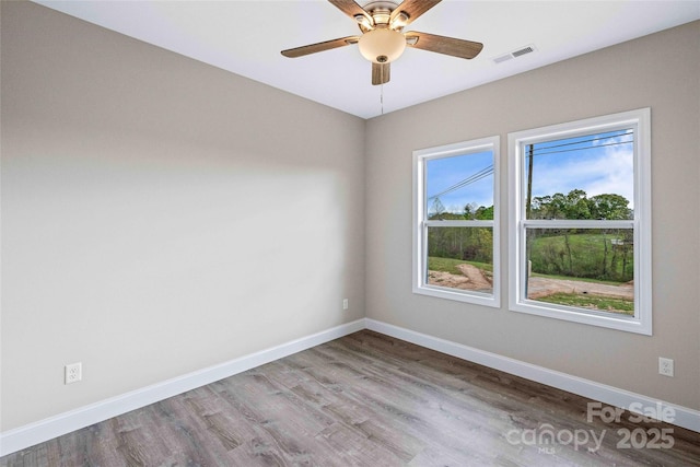 unfurnished room featuring a ceiling fan, wood finished floors, visible vents, and baseboards