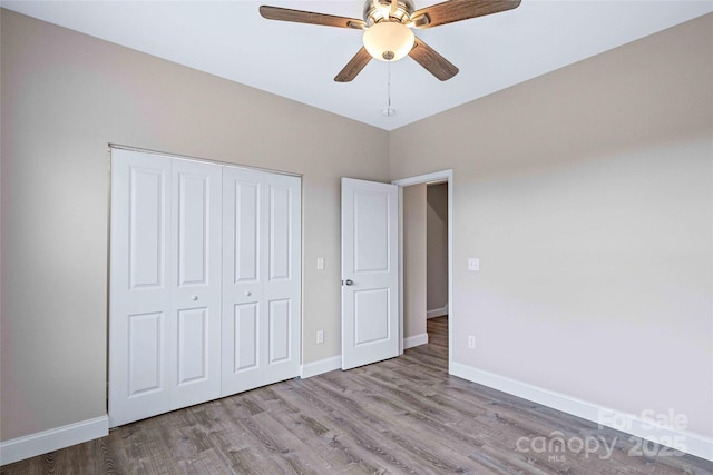 unfurnished bedroom featuring ceiling fan, a closet, wood finished floors, and baseboards