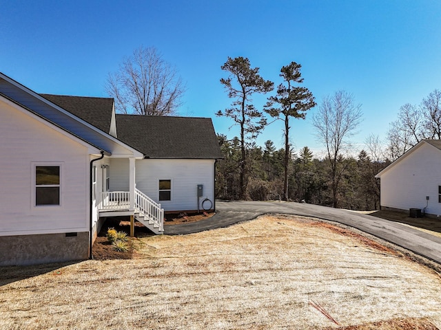 view of home's exterior featuring driveway, a shingled roof, crawl space, and central air condition unit