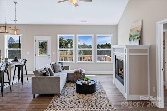 living room with a glass covered fireplace, visible vents, baseboards, and wood finished floors