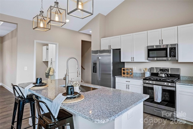 kitchen featuring dark wood-style flooring, a center island with sink, appliances with stainless steel finishes, white cabinetry, and a sink