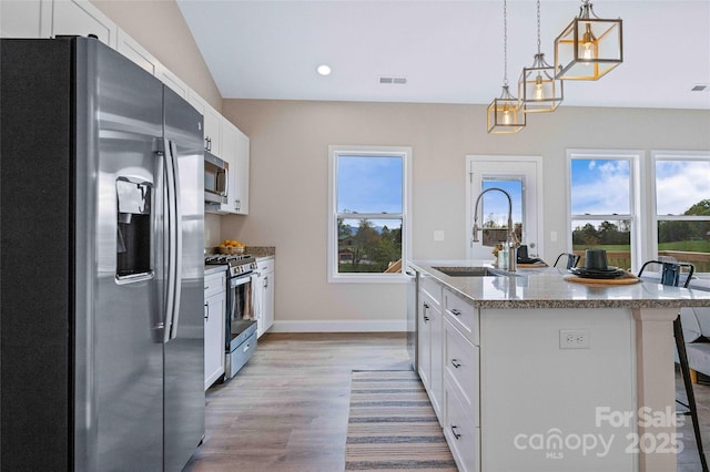 kitchen with wood finished floors, a sink, white cabinetry, appliances with stainless steel finishes, and a center island with sink