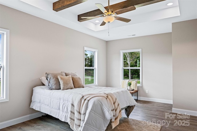 bedroom with a raised ceiling, wood finished floors, and baseboards