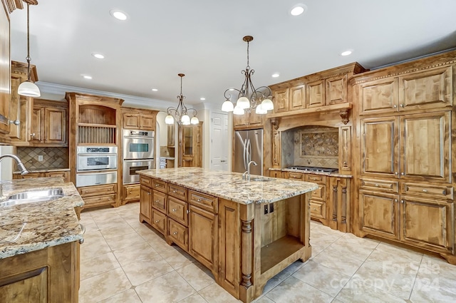 kitchen with light stone counters, a kitchen island with sink, sink, a notable chandelier, and appliances with stainless steel finishes