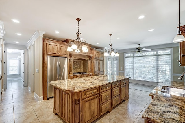 kitchen featuring light stone countertops, a kitchen island with sink, sink, hanging light fixtures, and appliances with stainless steel finishes