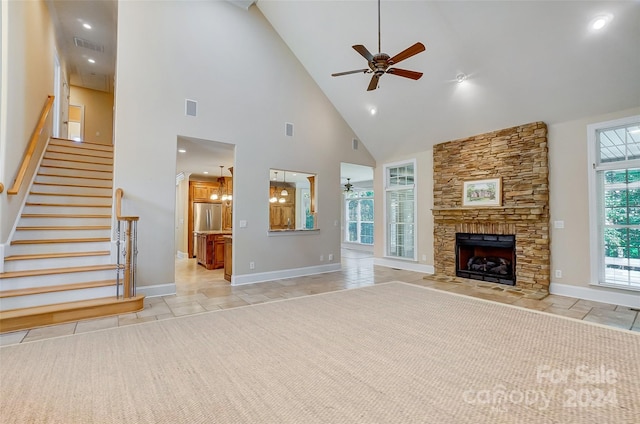 unfurnished living room with high vaulted ceiling, ceiling fan, and a stone fireplace