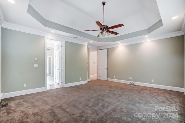 carpeted spare room with crown molding, a tray ceiling, and ceiling fan