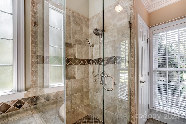 bathroom with plenty of natural light, crown molding, and a shower with door