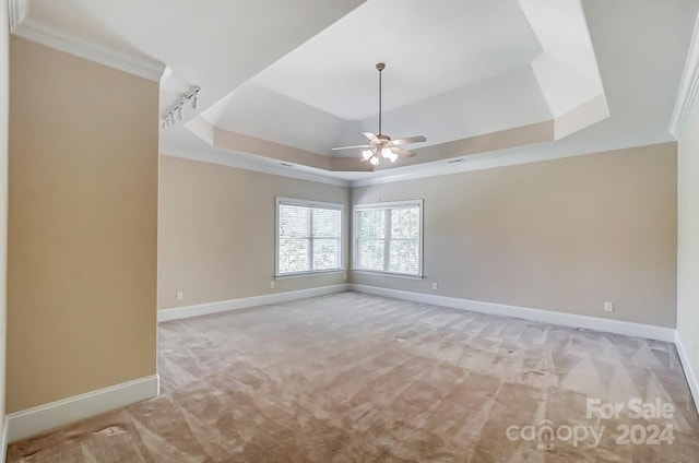 carpeted empty room featuring ceiling fan, crown molding, and a tray ceiling