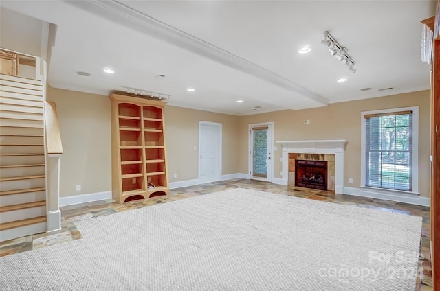 unfurnished living room featuring a fireplace, crown molding, and track lighting