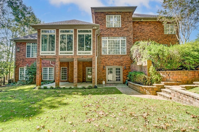 rear view of property featuring a yard, a patio, and french doors