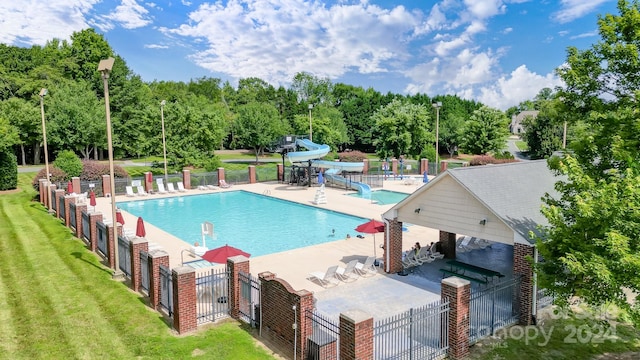 view of pool featuring a yard, a water slide, and a patio area