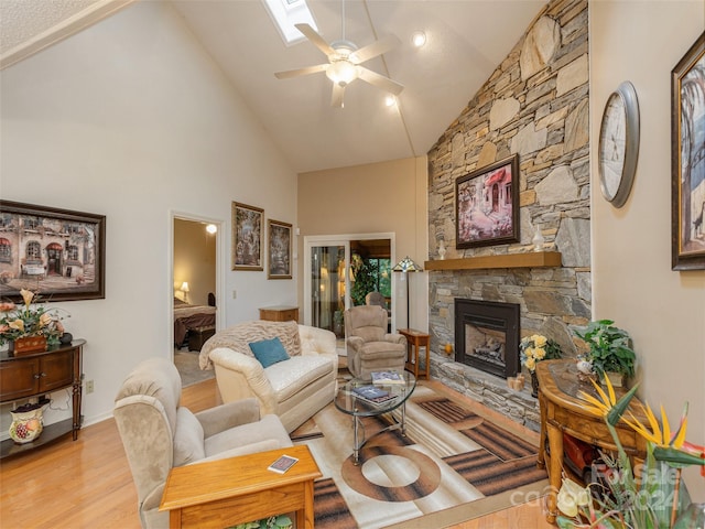 living room featuring high vaulted ceiling, ceiling fan, light hardwood / wood-style flooring, and a fireplace