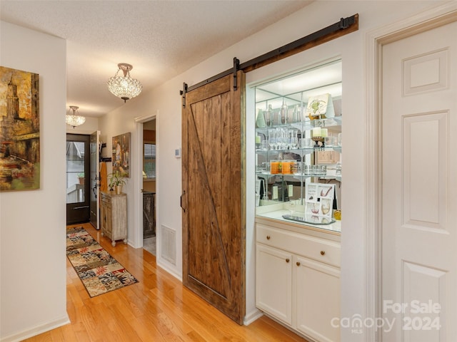 interior space with light wood-type flooring, a textured ceiling, and a barn door