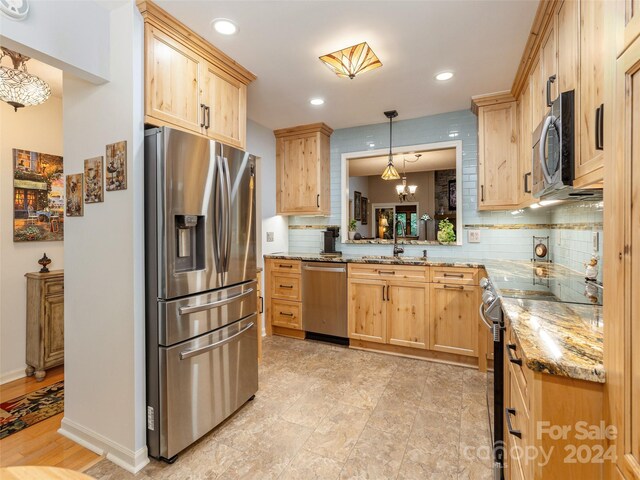 kitchen featuring light brown cabinetry, a chandelier, appliances with stainless steel finishes, and tasteful backsplash