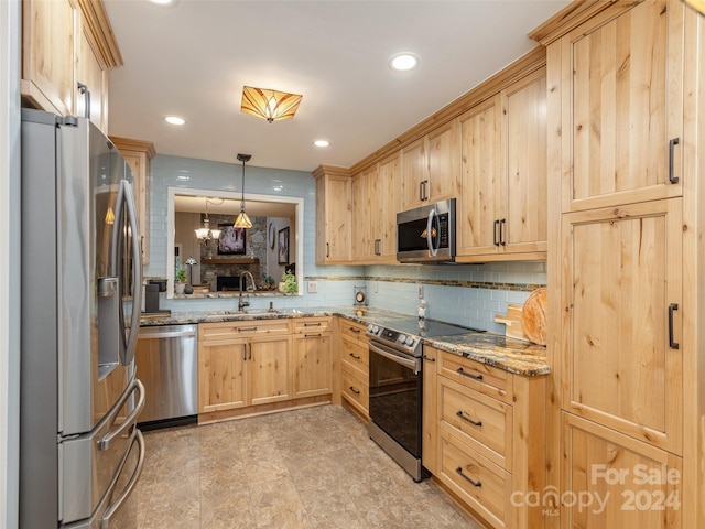 kitchen with light stone countertops, sink, pendant lighting, and stainless steel appliances