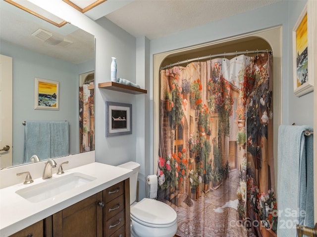 bathroom with a textured ceiling, vanity, and toilet