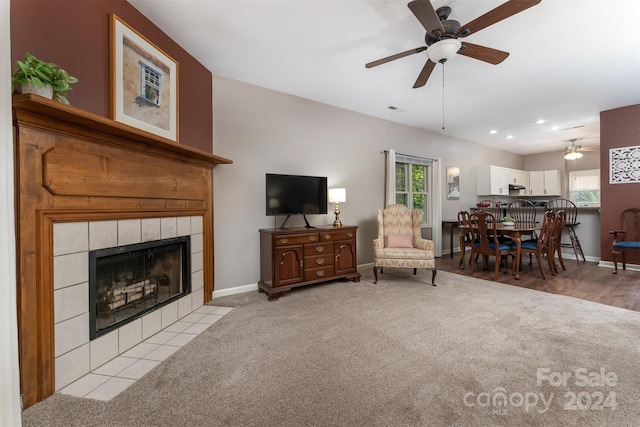 living room featuring a tile fireplace, light hardwood / wood-style floors, ceiling fan, and a healthy amount of sunlight