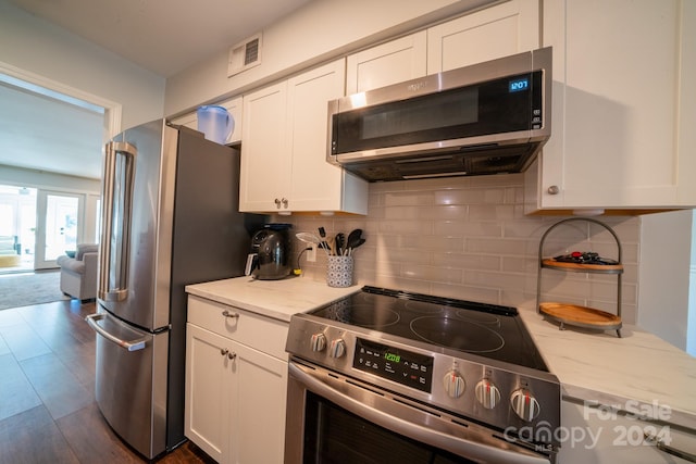 kitchen featuring appliances with stainless steel finishes, decorative backsplash, white cabinets, and dark hardwood / wood-style flooring