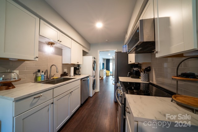 kitchen featuring appliances with stainless steel finishes, sink, backsplash, white cabinetry, and dark wood-type flooring