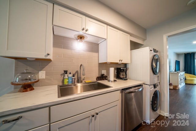 kitchen featuring dark wood-type flooring, stacked washer / drying machine, white cabinetry, and sink